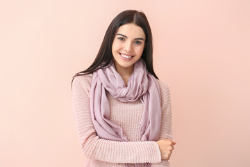 Fototapeta premium Beautiful young woman in warm sweater on color background