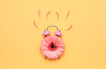 Creative alarm clock made with flower on color background