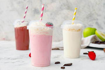 Cups of tasty milkshakes on white background