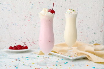 Glasses of tasty milkshakes on white background