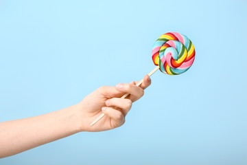 Female hand with sweet lollipop on color background