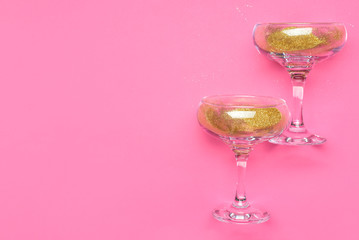 Glasses for champagne with glitter on color background