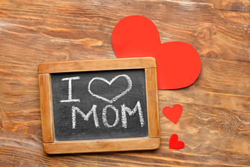 Chalkboard with text I LOVE MOM on wooden background