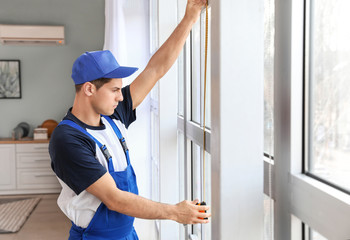 Male worker installing window in flat