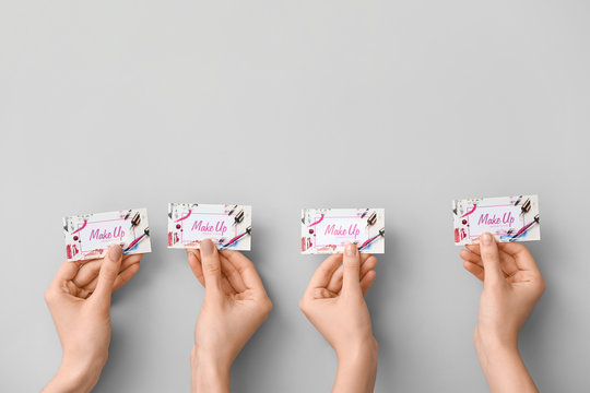 Female Hands With Business Cards Of Makeup Artist On Grey Background