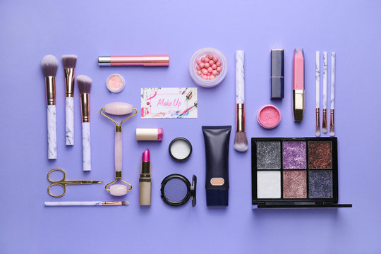 Decorative cosmetics and accessories with business card of makeup artist on color background