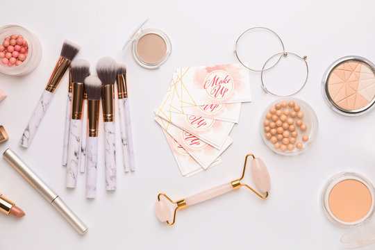 Decorative cosmetics and accessories with business cards of makeup artist on white background