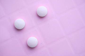 close up of white pills spilling on a white background 