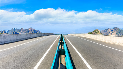 Fototapeta premium Empty asphalt road and green mountain with beautiful clouds,panoramic view.