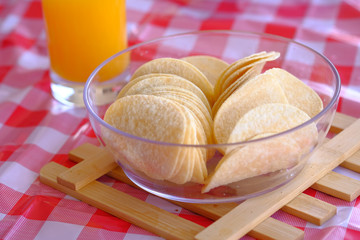 Potato chips and orange juice on a wooden table