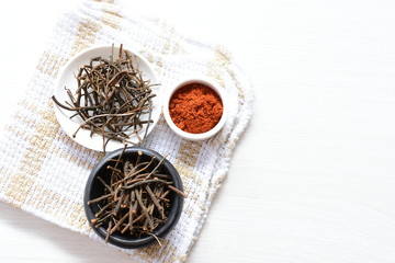 Saffron seasoning in root and powder, exhibited in containers on white wooden board