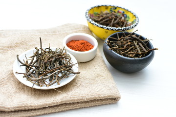 Fototapeta premium Saffron seasoning in root and powder, exhibited in containers on white wooden board