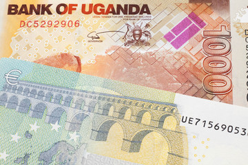 A five euro European bank note with a one thousand Ugandan shilling bill close up in macro