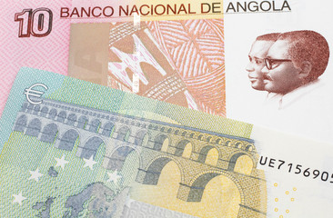 A colorful ten kwanza bill from Angola with a blue and green, European 5 euro bank note close up in macro