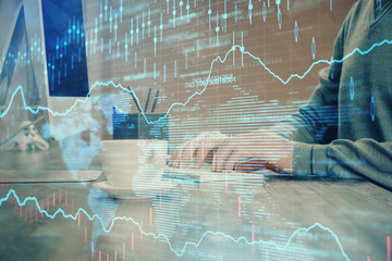 Multi exposure of graph with man typing on computer in office on background. Concept of hard work.