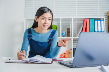 Young asian woman reading news and feed in social media on laptop, Attractive female looking new product and promotion shopping online for lowest price, feeling happy.