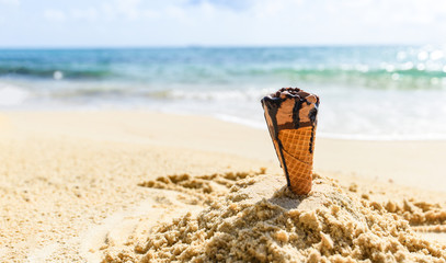 Ice cream cone on sand beach background - Melting ice cream on beach sea in summer hot weather...