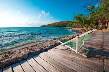 Obraz premium Terrace view of sea waves and coast landscape seascape rock with bench chair beach on wooden balcony - Tropical island with ocean blue sky and resort background in Thailand summer beach vacation