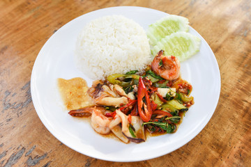 Stir fried seafood squid shrimp prawn with holy basil and rice - Thai food spicy fried recipe with cucumber and chili