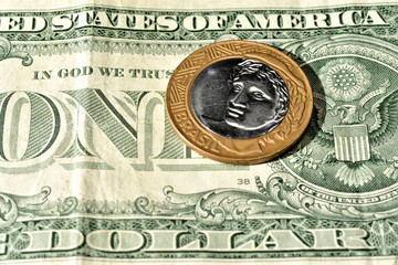 Close up de Moeda de 1 Real brasileiro acima de uma nota de Dólar americano