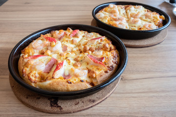 Set of delicious seafood pizza topped with cheese, pineapple, crab sticks and shrimp on wooden table. Pizza is a favorite food for many around the world.
