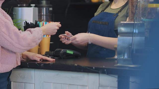 close view cafe bar girl employee performs order payment taking woman client credit card and using terminal
