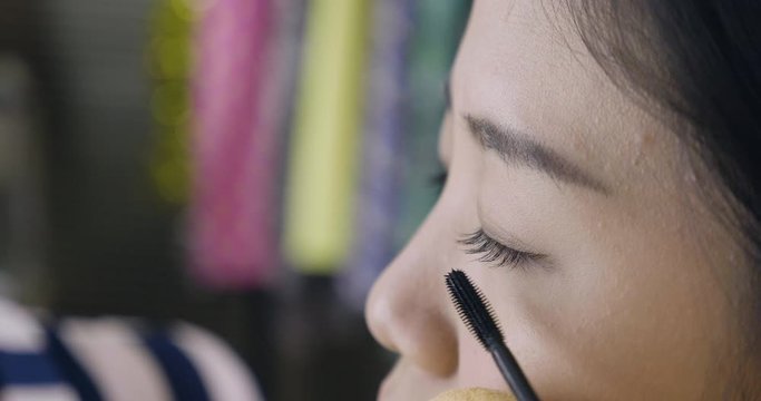 slow motion of close up asian girl model face while talent makeup artist lady painting mascara on eyelash. young famous woman celebrity applying make up from beauty worker in backstage dressing room.