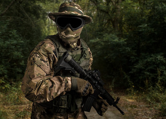 Low key side portrait  soldier in military camouflage uniform protected with helmet, body armour ,...