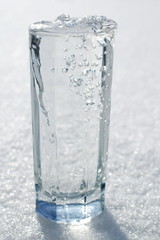 glass full to the brim of fresh crystal clear transparent water with a frozen sheen on the white cold snow