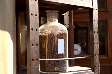 Coffee background. Side view of a dirty jar with coffee beans. Coffee beans in a jar on a window. Street trading. Side view, close-up, horizontal, no people, cropped shot. Coffee concept.