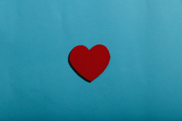 Medical background. On a blue background the figure of a red heart in the center. Abstract background with a red heart in the center of the frame. A lot of free space for text, horizontal, closeup.