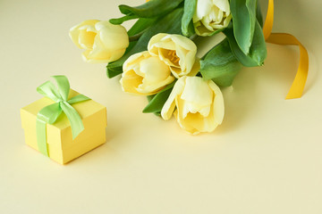 Bouquet of yellow tulips with gift box on a light background