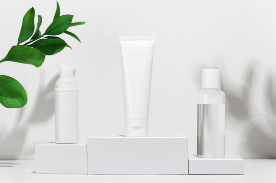 Cream tube, moisturizing foam in spray and tonic water on shipping boxes. White blank unbranded flacons with cosmetology products. Professional skincare and wellness concept