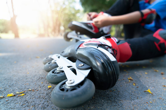 Little boy setting of laces on black roller skates