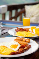American breakfast with sunny side up eggs, bacon and juice