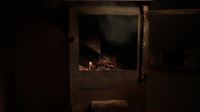 Fire burning in small black iron stove. Traditional Azerbaijani nut stove. Closeup photo with selective focus