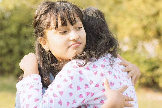 Concept of fake hug, friendship, embracing or two faced - Young teenager Hypocritical girl embracing sad friend at park.