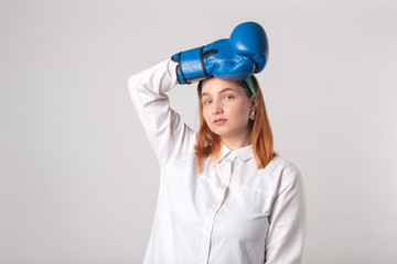 Girl power concept. Confident young woman isolated on gray wall background. Feminine and independent strength.Girl in boxing gloves. Female power concept. Boxing gloves on a girl.