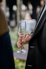 A man in a black suit Holding a champagne glass.