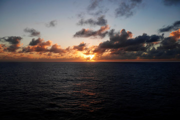 Fototapeta na wymiar An orange sunset over a calm Caribbean Sea seen from a cruise ship