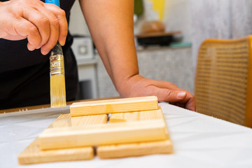 Girl varnishes a wooden detail.