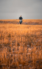 moody portrait of a solo traveller walking through colorful and endless fields alone by himself and enjoying the beautiful nature and silence and peace of it.