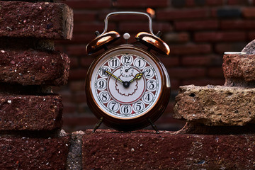 Vintage alarm clock on a red brick wall