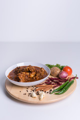 Hot and spicy Singapore's national dish the sup tulang made out of mutton bone marrow in a white bowl and white background