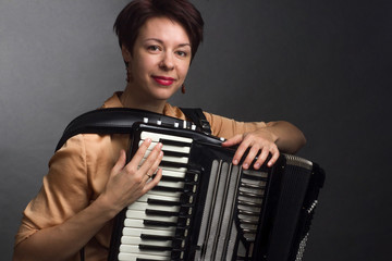 A brunette in a gold shirt, with short haircut, on a light gray background of the Studio. With accordion musician