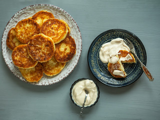 Light breakfast with dairy products cottage cheese pancakes and sour cream, served on two plates