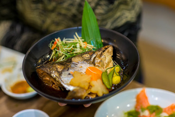 Japanese food concept. Salmon head steamed with sweet sauce and vegetable in Japanese style. Salmon kabutoni steamed, Japanese food style. Salmon head boiled in soy sauce with vegetables. 