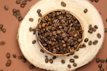 coffee beans in a wooden round cup on a cut of a tree on a  brown background.Coffee drink.Coffee beans in a minimalist style.top view