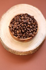 coffee beans in a wooden round cup on a cut of a tree on a dark brown background.Coffee drink.Coffee beans in a minimalist style.