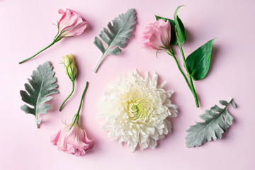 Romantic flower arrangement of white chrysanthemums and pink lisianthus flowers, on pastel pink background, photographed from above.